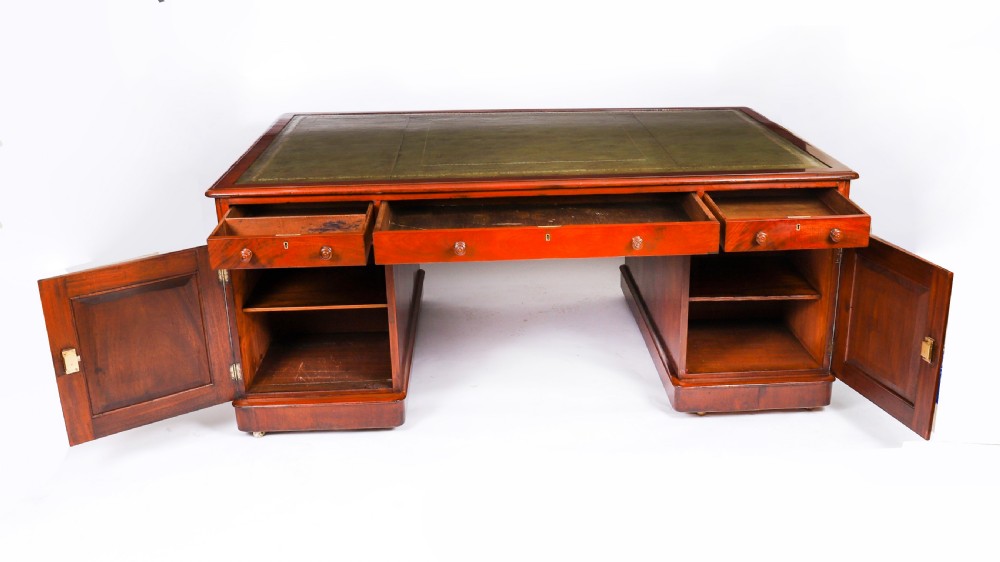 A Victorian flame mahogany partners pedestal desk fitted with a green leather inset top and wooden knob drawer pulls. View XVI