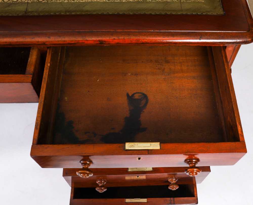 A Victorian flame mahogany partners pedestal desk fitted with a green leather inset top and wooden knob drawer pulls. View XVII