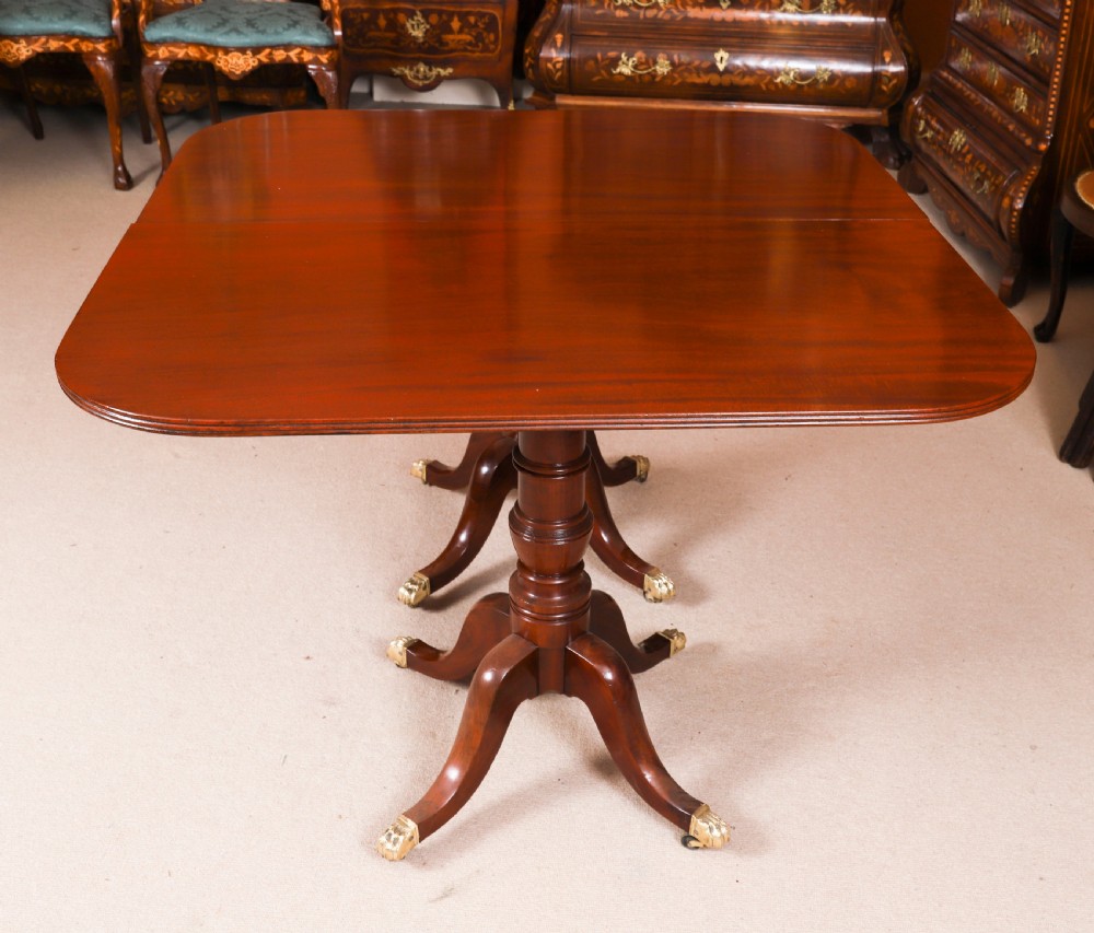 A George III Regency period mahogany twin pillar dining table featuring reeded edge detail and tripod pedestal legs with brass castors. View V