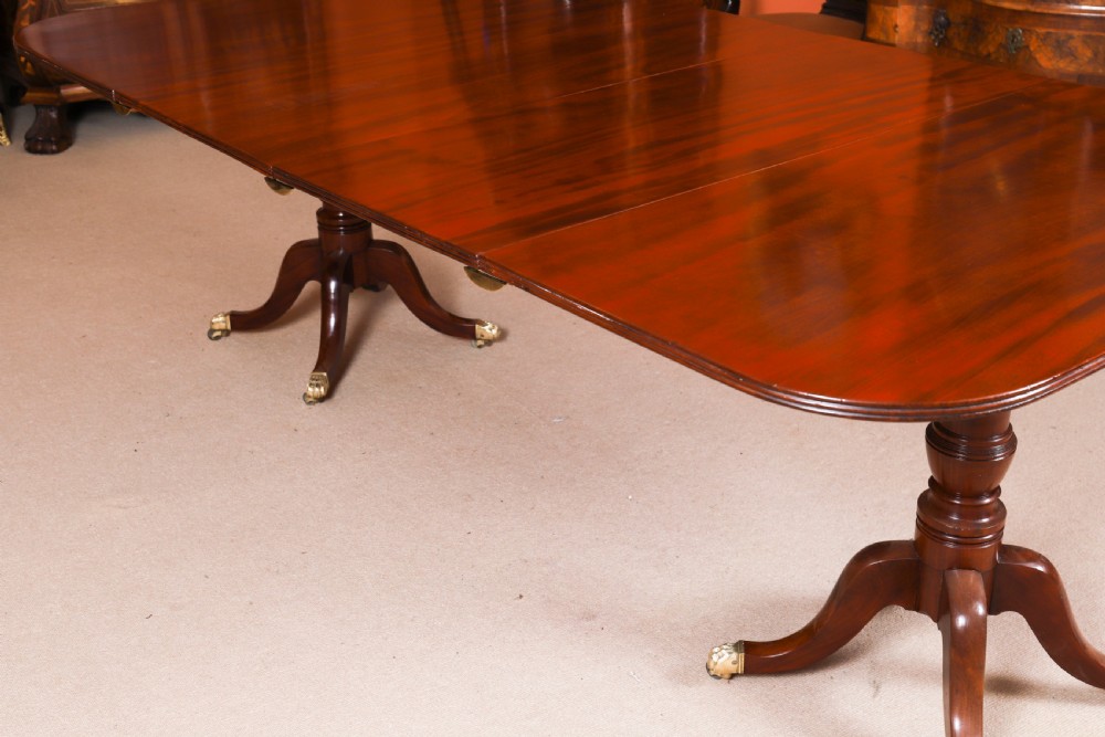 A George III Regency period mahogany twin pillar dining table featuring reeded edge detail and tripod pedestal legs with brass castors. View VI