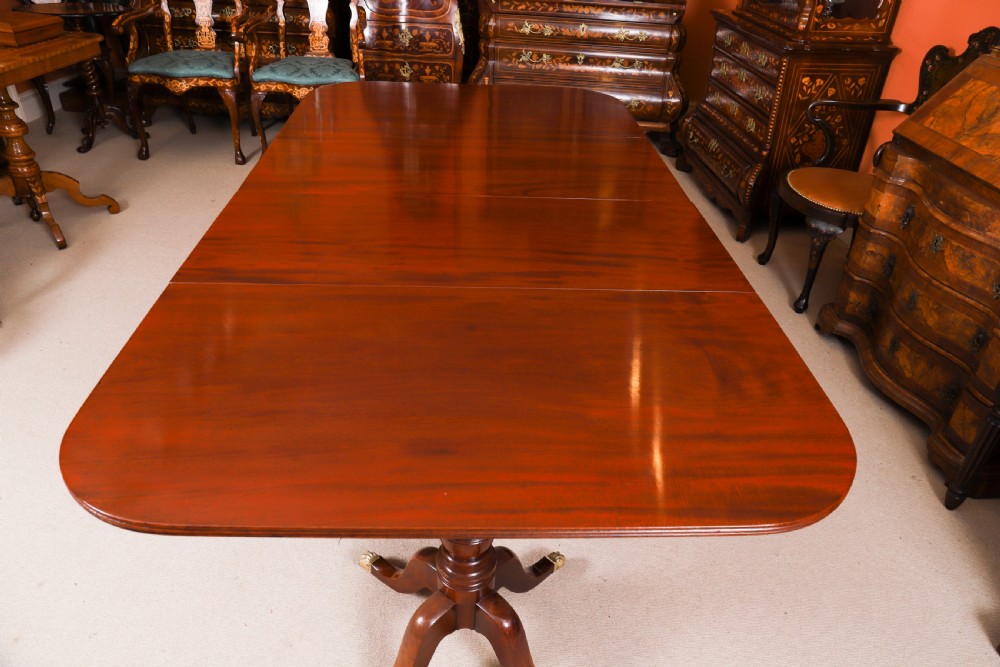 A George III Regency period mahogany twin pillar dining table featuring reeded edge detail and tripod pedestal legs with brass castors. View VII