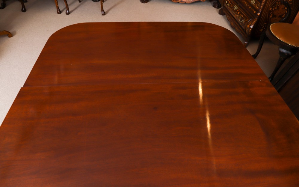 A George III Regency period mahogany twin pillar dining table featuring reeded edge detail and tripod pedestal legs with brass castors. View IX