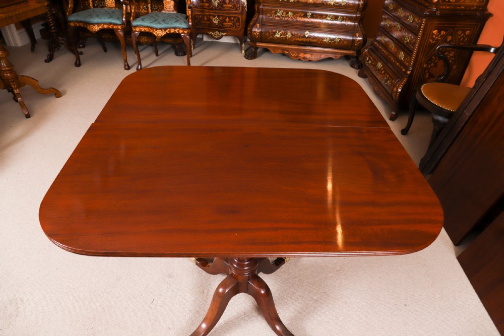 A George III Regency period mahogany twin pillar dining table featuring reeded edge detail and tripod pedestal legs with brass castors. View XI