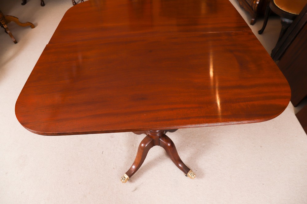 A George III Regency period mahogany twin pillar dining table featuring reeded edge detail and tripod pedestal legs with brass castors. View XII