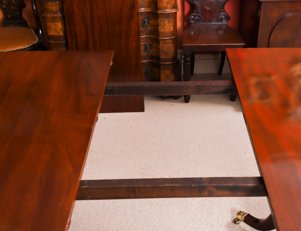 A George III Regency period mahogany twin pillar dining table featuring reeded edge detail and tripod pedestal legs with brass castors. View XIII