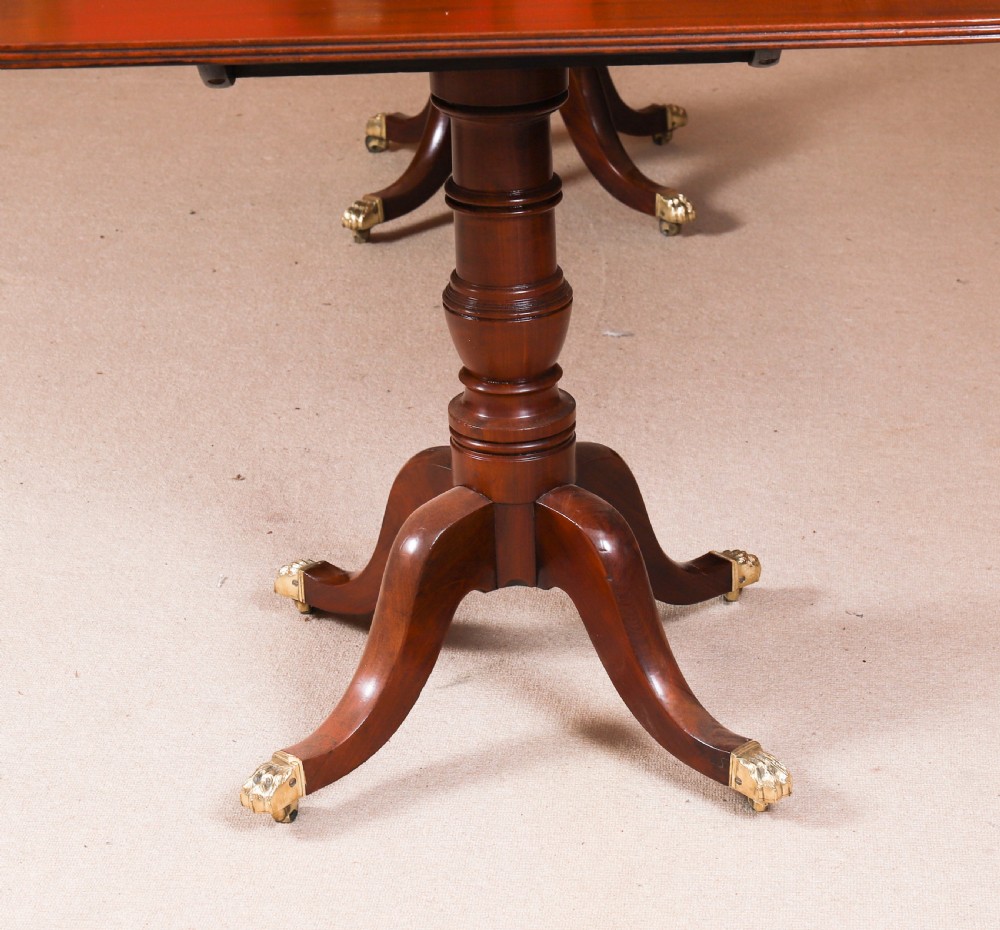 A George III Regency period mahogany twin pillar dining table featuring reeded edge detail and tripod pedestal legs with brass castors. View XIV