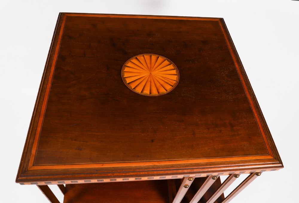 An Edwardian flame mahogany revolving bookcase featuring two tiers, vertical slatted sides with brass studs, satinwood inlay, and castors. View VI