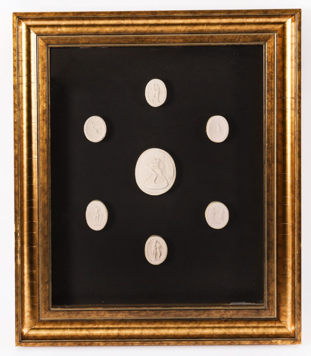 A pair of gold giltwood frames displaying classical white plaster intaglio casts arranged symmetrically against a dark background. View III