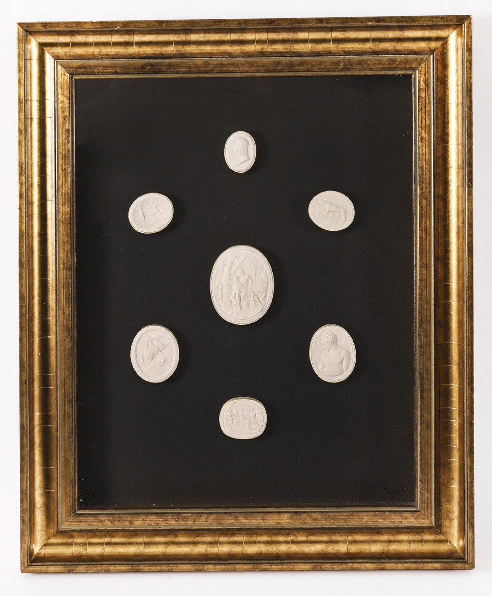 A pair of gold giltwood frames displaying classical white plaster intaglio casts arranged symmetrically against a dark background. View VII