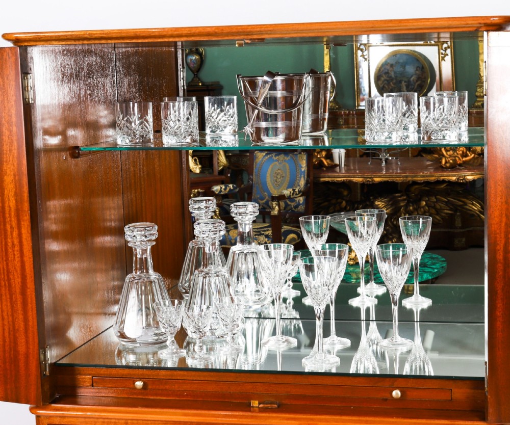 An Art Deco burr walnut cocktail cabinet featuring marquetry floral medallions, brass handles, two drawers, and cabriole legs against a white background. View IV