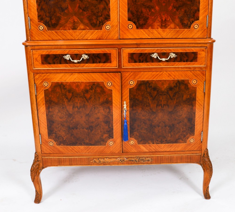 An Art Deco burr walnut cocktail cabinet featuring marquetry floral medallions, brass handles, two drawers, and cabriole legs against a white background. View VII