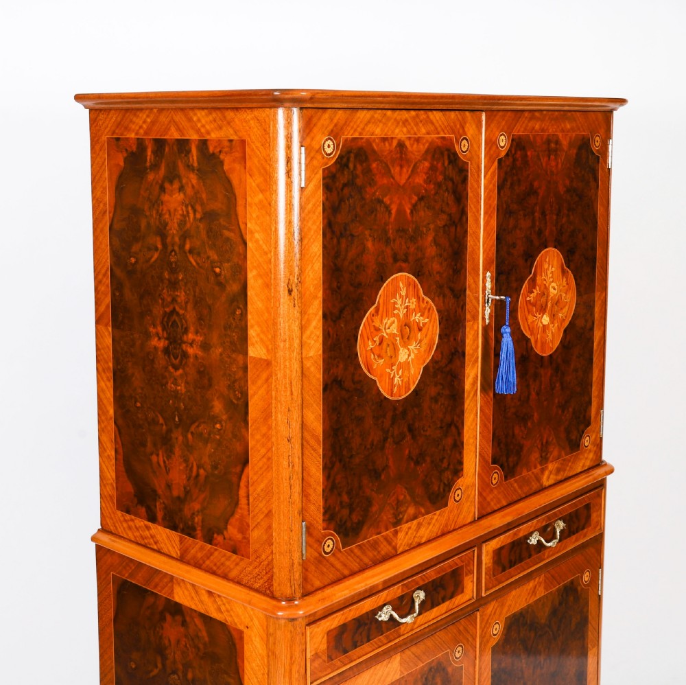 An Art Deco burr walnut cocktail cabinet featuring marquetry floral medallions, brass handles, two drawers, and cabriole legs against a white background. View VIII