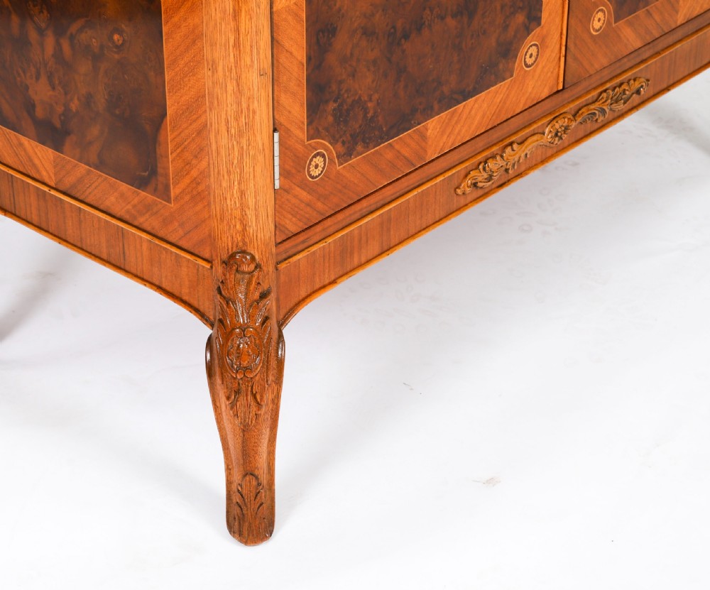 An Art Deco burr walnut cocktail cabinet featuring marquetry floral medallions, brass handles, two drawers, and cabriole legs against a white background. View XIII
