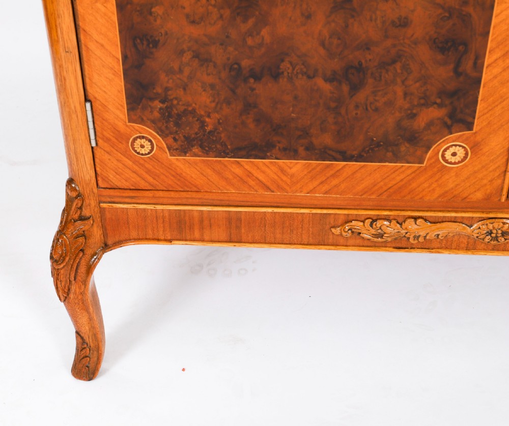 An Art Deco burr walnut cocktail cabinet featuring marquetry floral medallions, brass handles, two drawers, and cabriole legs against a white background. View XIV