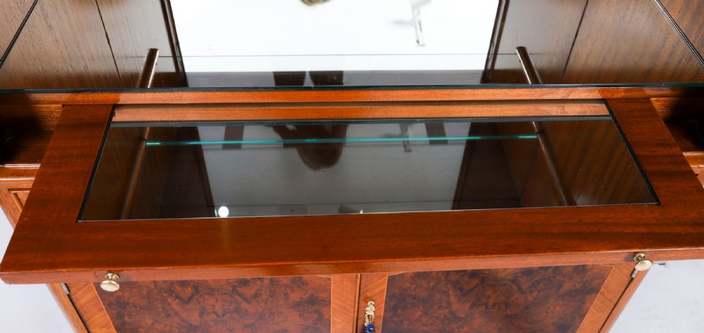 An Art Deco burr walnut cocktail cabinet featuring marquetry floral medallions, brass handles, two drawers, and cabriole legs against a white background. View XIX