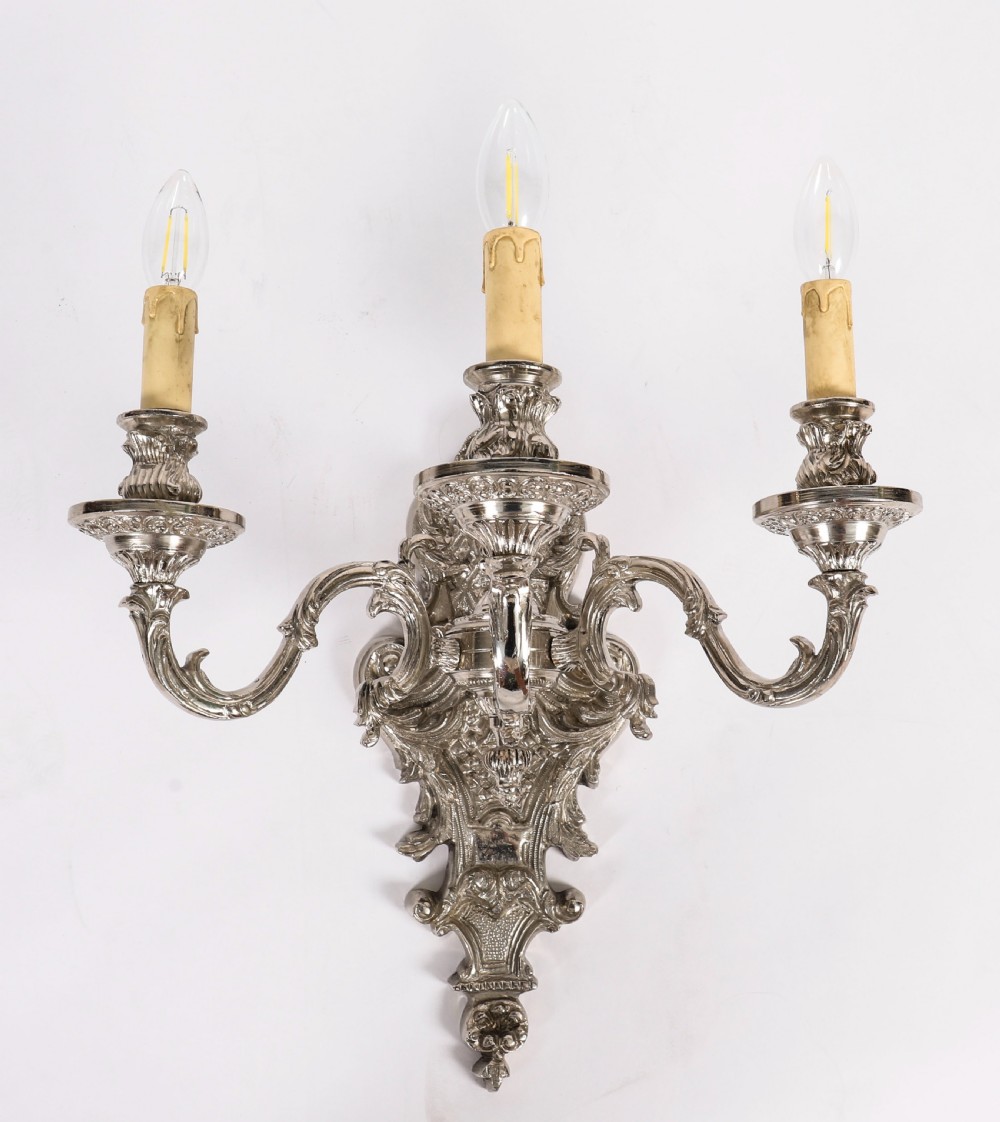 A matching set of four silver-plated three-arm French Rococo style wall appliques featuring ornate foliage scrollwork and candle-shaped bulb holders. View III