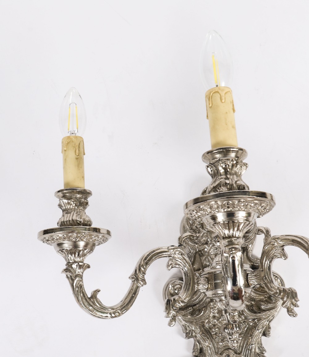 A pair of ornate silver-plated French wall sconces with three scrolling candle arms and detailed acanthus leaf decoration. View VI