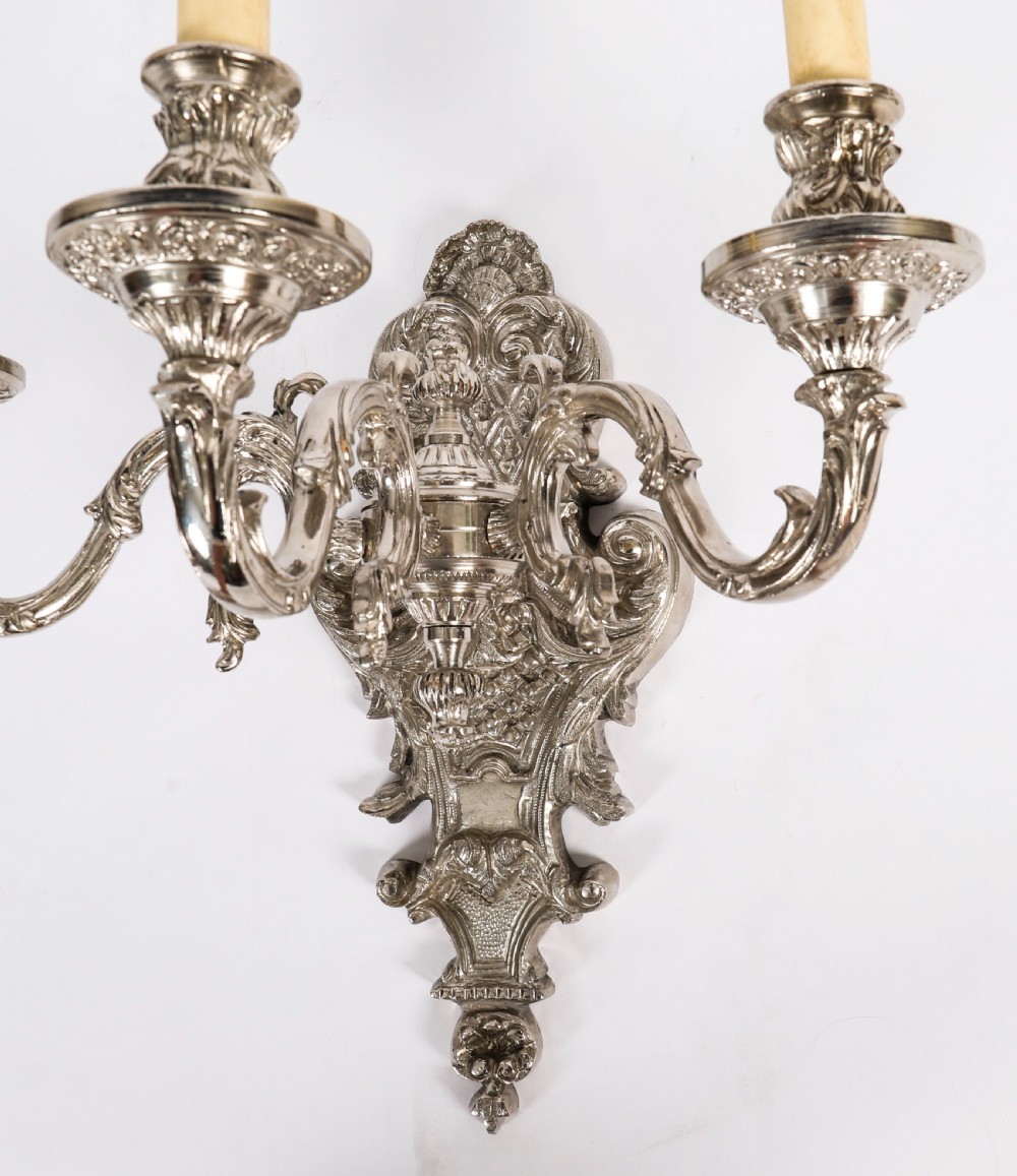 A pair of ornate silver-plated French wall sconces with three scrolling candle arms and detailed acanthus leaf decoration. View VIII