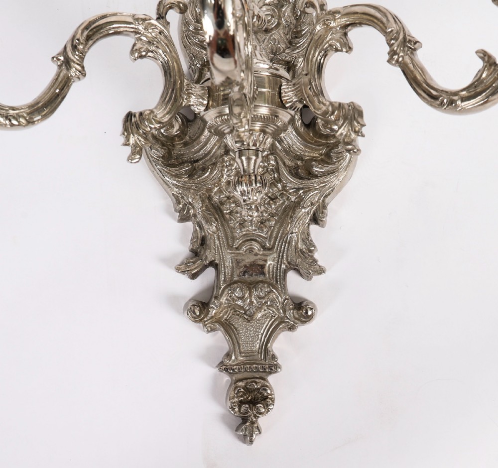 A pair of ornate silver-plated French wall sconces with three scrolling candle arms and detailed acanthus leaf decoration. View IX