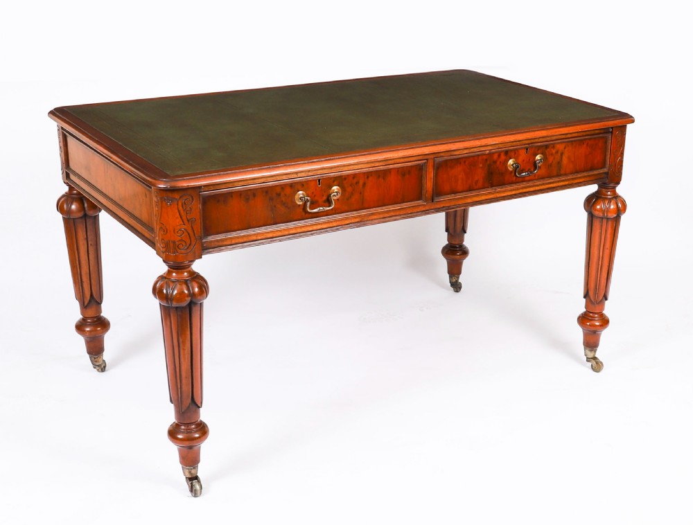 Nineteenth-century Victorian mahogany writing table featuring a green leather inset top, two drawers with brass drop handles, and carved turned legs on brass castors.