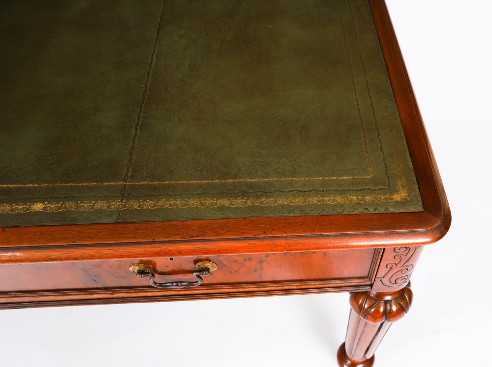 Nineteenth-century Victorian mahogany writing table featuring a green leather inset top, two drawers with brass drop handles, and carved turned legs on brass castors. View VI