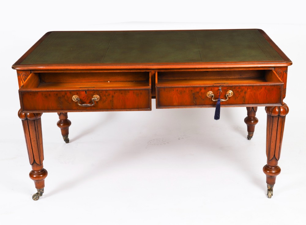 Nineteenth-century Victorian mahogany writing table featuring a green leather inset top, two drawers with brass drop handles, and carved turned legs on brass castors. View VII