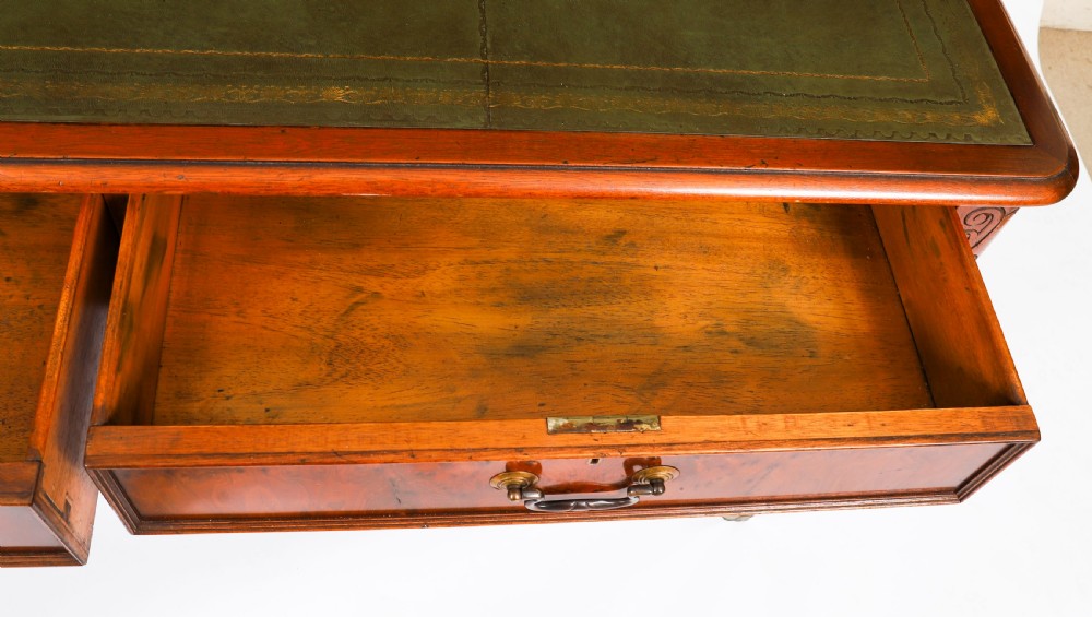 Nineteenth-century Victorian mahogany writing table featuring a green leather inset top, two drawers with brass drop handles, and carved turned legs on brass castors. View XI