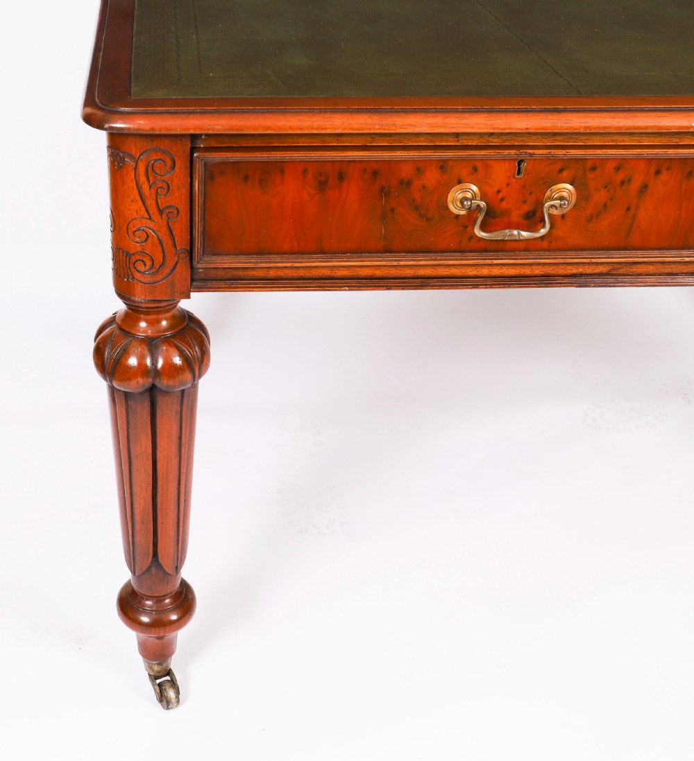 Nineteenth-century Victorian mahogany writing table featuring a green leather inset top, two drawers with brass drop handles, and carved turned legs on brass castors. View XII