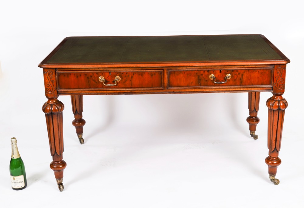Nineteenth-century Victorian mahogany writing table featuring a green leather inset top, two drawers with brass drop handles, and carved turned legs on brass castors. View XIII