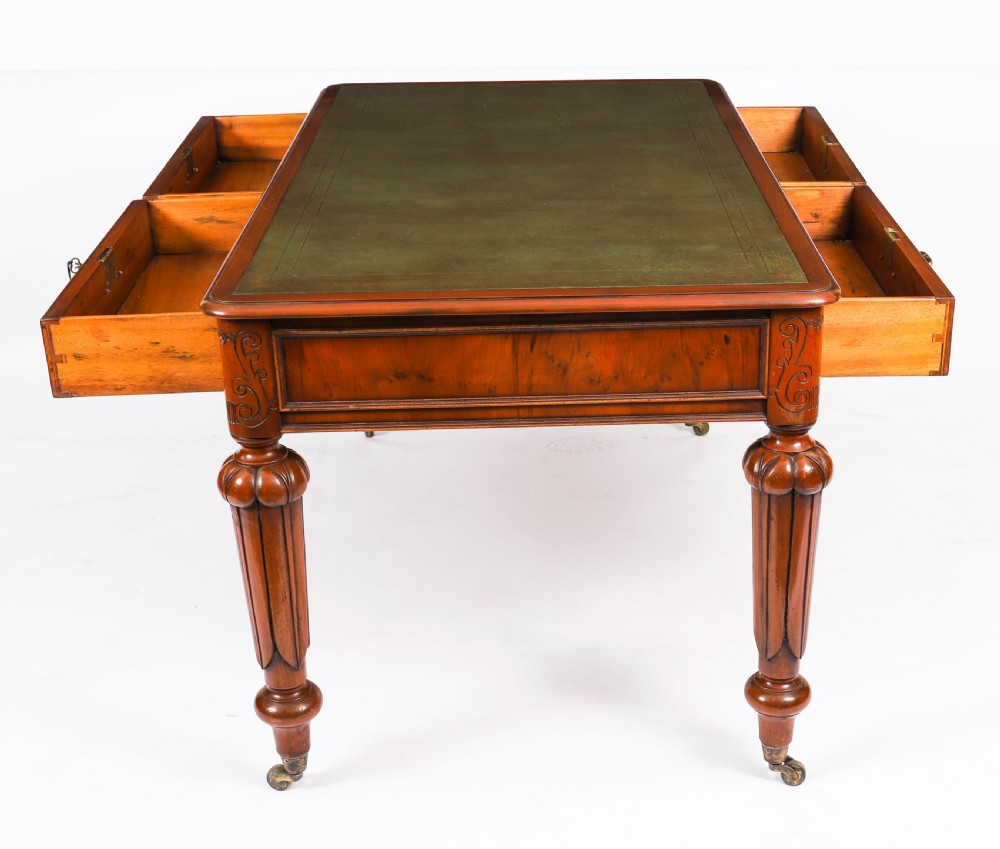 Nineteenth-century Victorian mahogany writing table featuring a green leather inset top, two drawers with brass drop handles, and carved turned legs on brass castors. View XIV