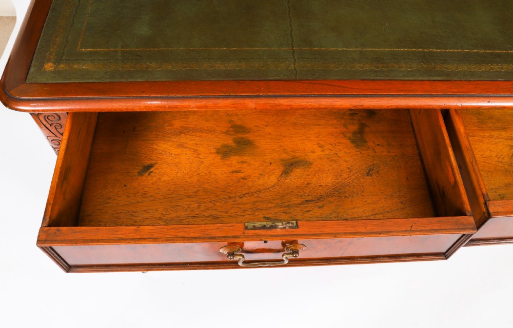 Nineteenth-century Victorian mahogany writing table featuring a green leather inset top, two drawers with brass drop handles, and carved turned legs on brass castors. View XVI