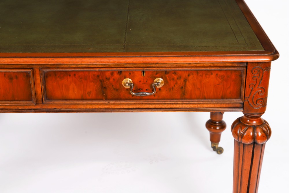Nineteenth-century Victorian mahogany writing table featuring a green leather inset top, two drawers with brass drop handles, and carved turned legs on brass castors. View XIX