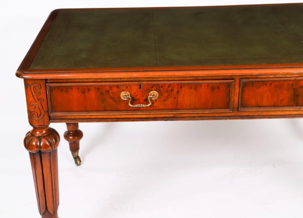 Nineteenth-century Victorian mahogany writing table featuring a green leather inset top, two drawers with brass drop handles, and carved turned legs on brass castors. View XX