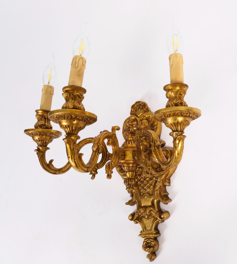 A set of eight French gilt bronze three-arm wall appliques featuring ornate foliate castings and candle-style fittings. View III