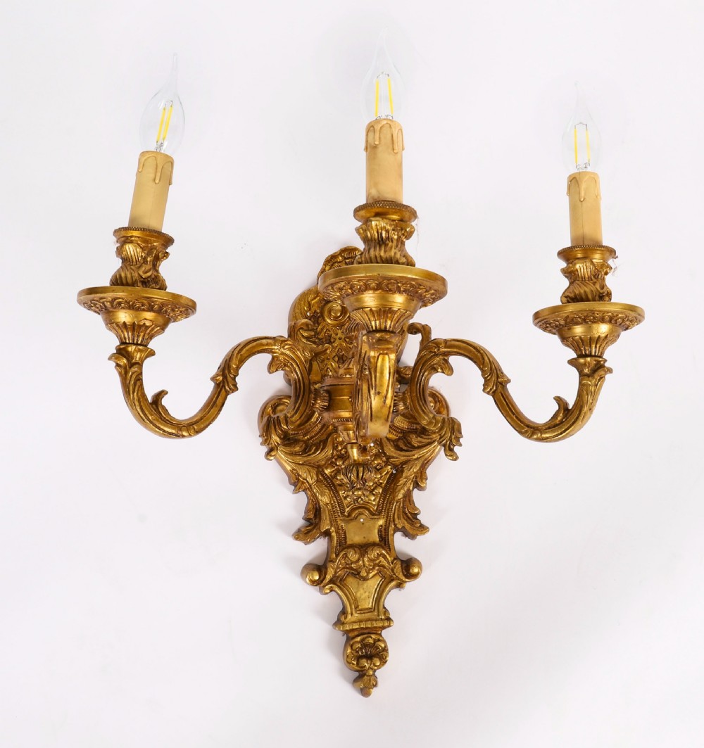 A set of eight French gilt bronze three-arm wall appliques featuring ornate foliate castings and candle-style fittings. View IV