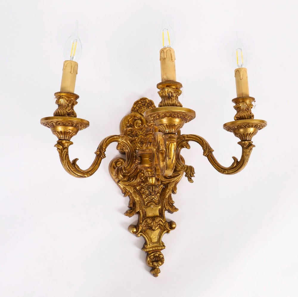 A set of eight French gilt bronze three-arm wall appliques featuring ornate foliate castings and candle-style fittings. View IX
