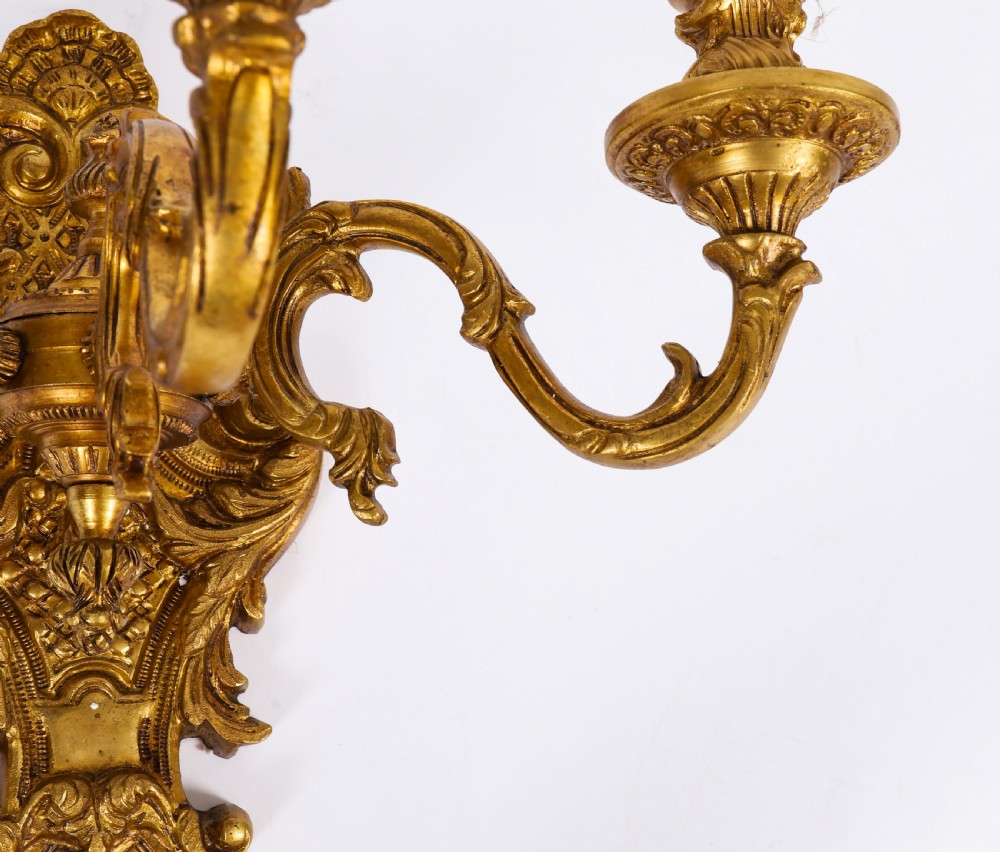 A set of eight French gilt bronze three-arm wall appliques featuring ornate foliate castings and candle-style fittings. View XI