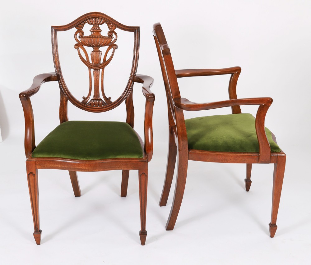 A set of eight Edwardian mahogany dining chairs featuring carved shield backs with urn splats and green velvet upholstered seats. View II