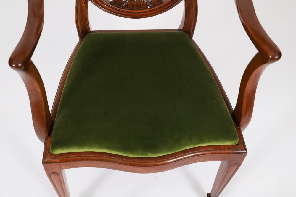 A set of eight Edwardian mahogany dining chairs featuring carved shield backs with urn splats and green velvet upholstered seats. View VI