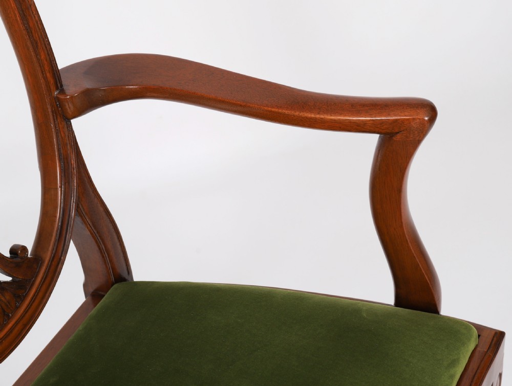 A set of eight Edwardian mahogany dining chairs featuring carved shield backs with urn splats and green velvet upholstered seats. View IX