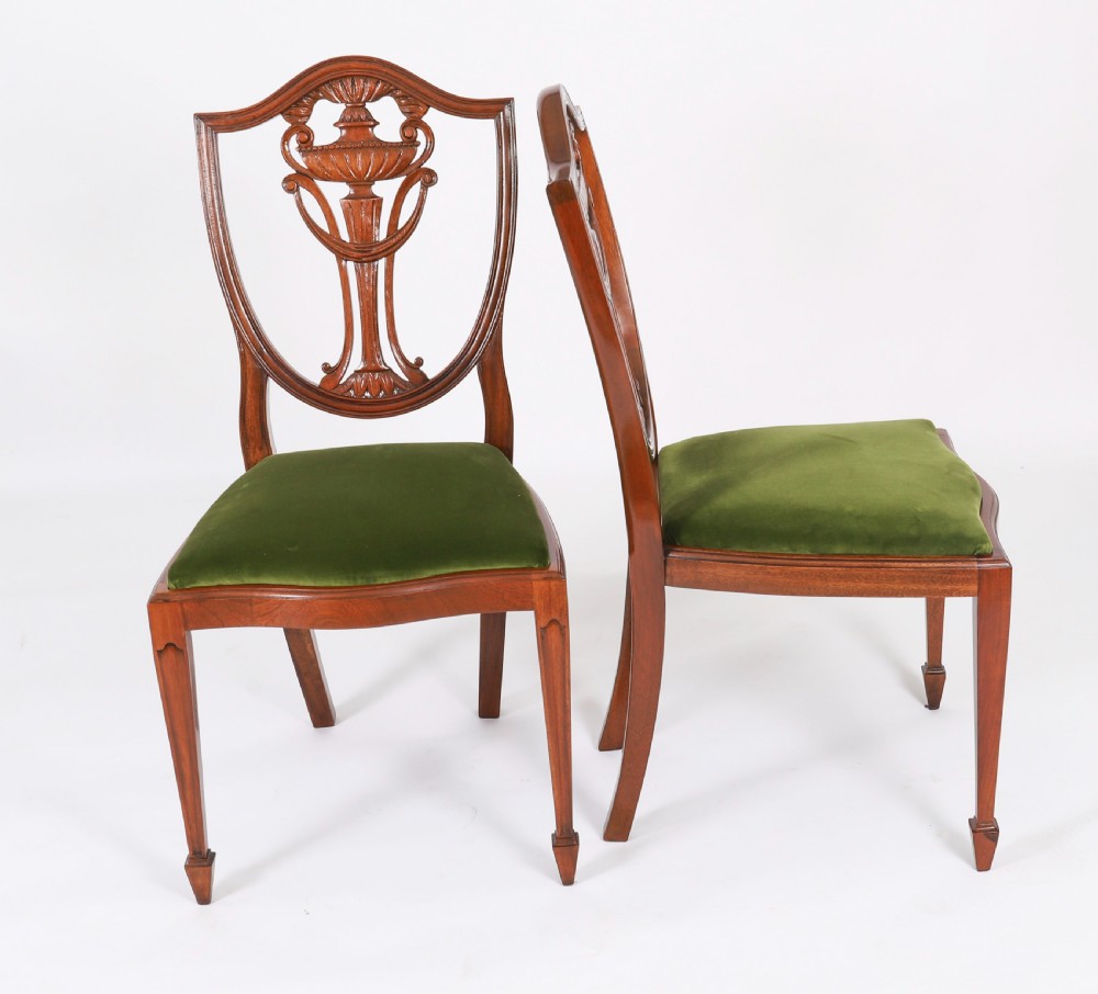 A set of eight Edwardian mahogany dining chairs featuring carved shield backs with urn splats and green velvet upholstered seats. View XII