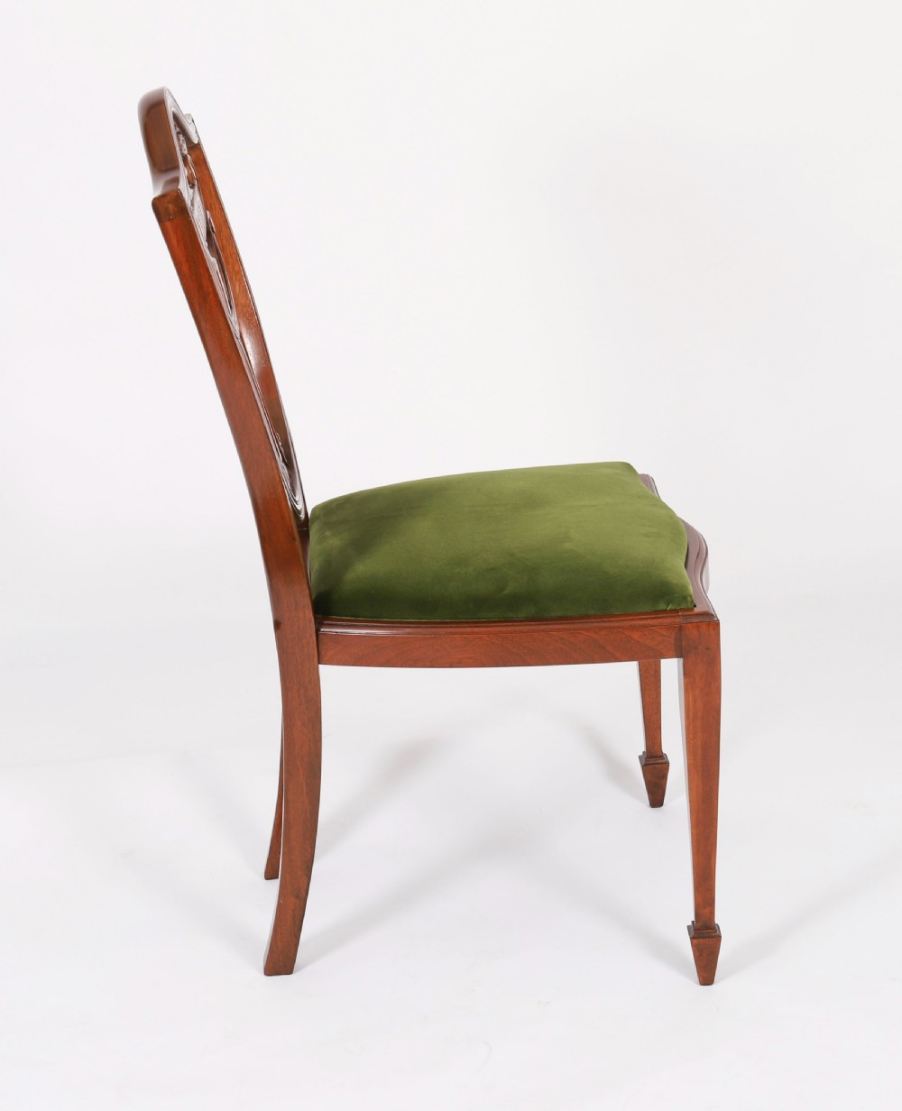 A set of eight Edwardian mahogany dining chairs featuring carved shield backs with urn splats and green velvet upholstered seats. View XIV