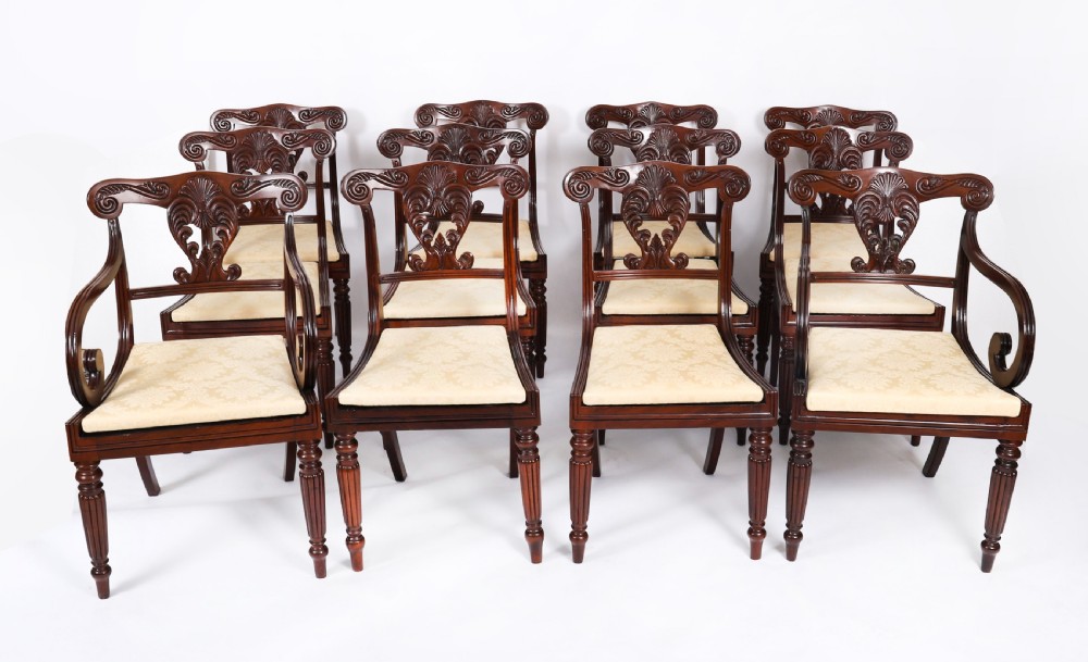 A set of twelve nineteenth-century Irish Regency mahogany dining chairs with carved shell back crests and cream upholstered seats.