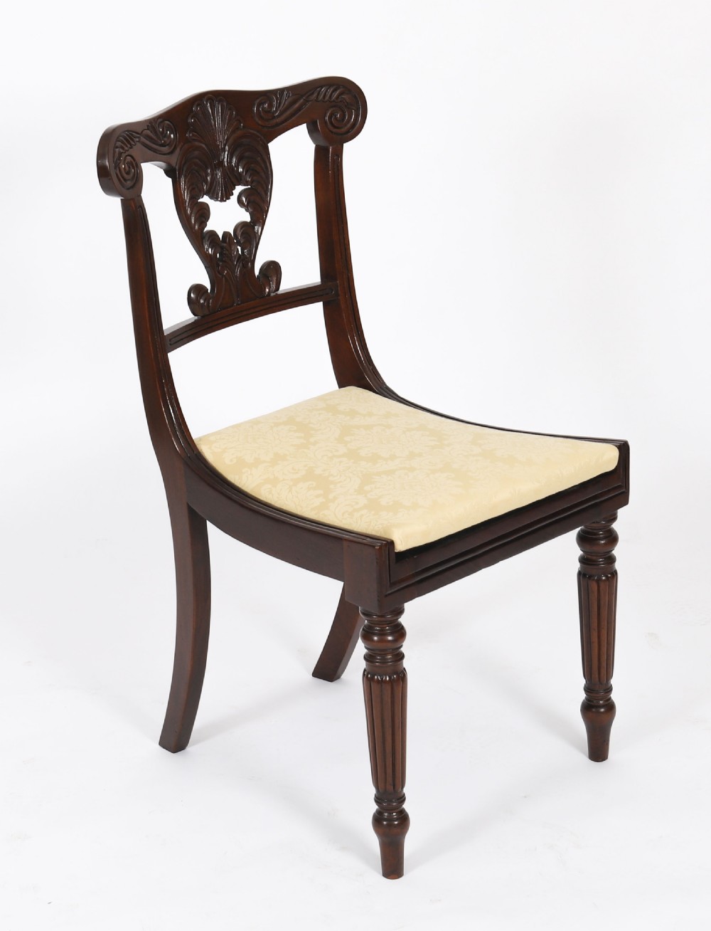 A set of twelve nineteenth-century Irish Regency mahogany dining chairs with carved shell back crests and cream upholstered seats. View III