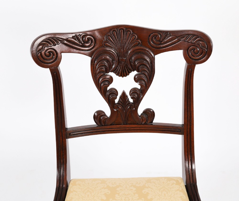 A set of twelve nineteenth-century Irish Regency mahogany dining chairs with carved shell back crests and cream upholstered seats. View V