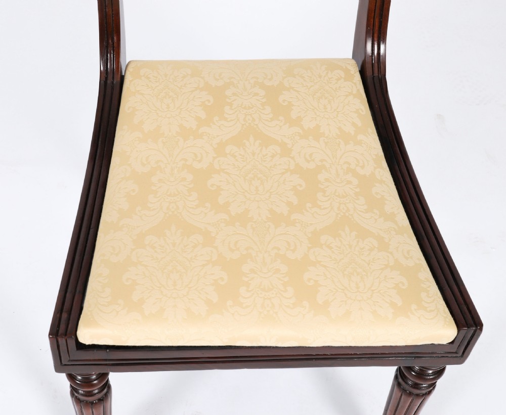 A set of twelve nineteenth-century Irish Regency mahogany dining chairs with carved shell back crests and cream upholstered seats. View VIII