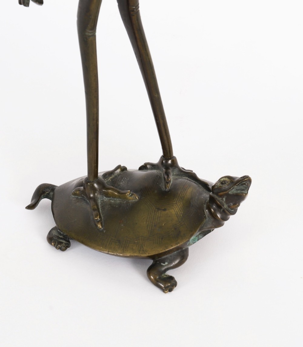 A pair of 19th-century Japanese dark bronze pricket candlesticks formed as cranes standing on tortoises holding lotus stems in their beaks. View VIII