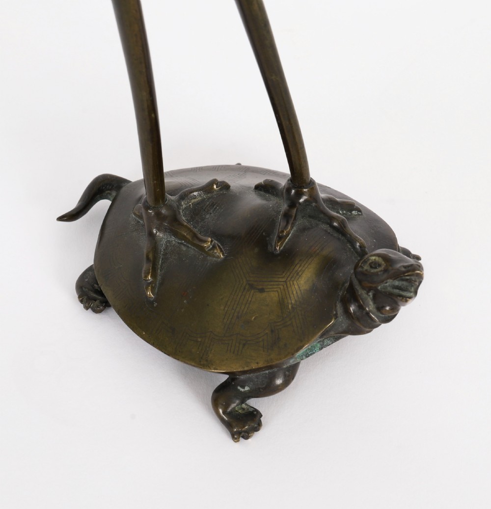 A pair of 19th-century Japanese dark bronze pricket candlesticks formed as cranes standing on tortoises holding lotus stems in their beaks. View XVI