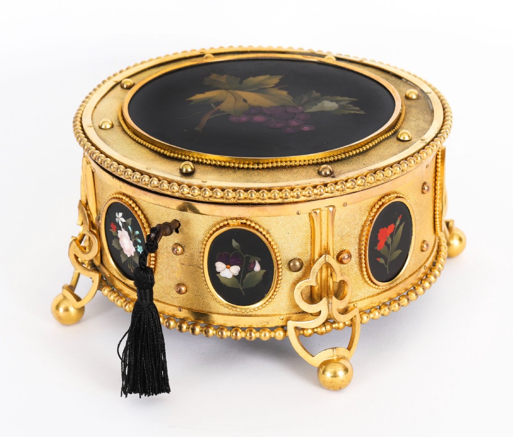 A circular 19th-century ormolu jewellery casket featuring fine Pietra Dura floral and fruit stone inlays set into gilt bronze with a key and tassel. View II