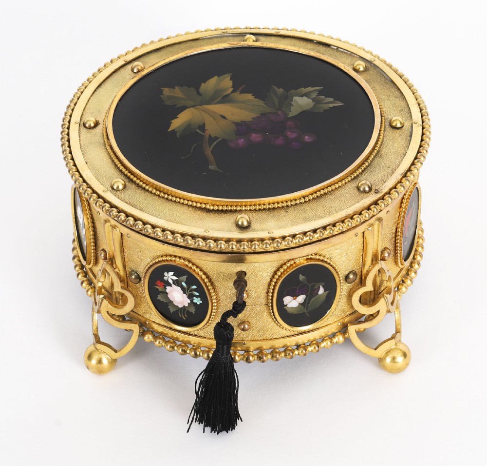 A circular 19th-century ormolu jewellery casket featuring fine Pietra Dura floral and fruit stone inlays set into gilt bronze with a key and tassel. View XIV